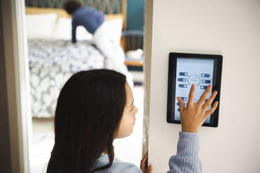 Mädchen berührt den Bildschirm eines Heimautomatisierungsgeräts an der Wand zu Hause - MASF30359