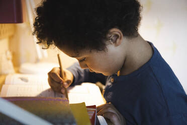 Boy writing in book while doing homework - MASF30368