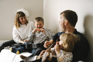 Parents talking with son having down syndrome sitting in bedroom at home - MASF30413