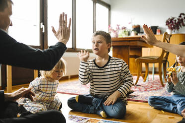 Eltern, die mit ihrem Sohn, der das Down-Syndrom hat, im Wohnzimmer zu Hause sitzen, High-Five machen - MASF30418