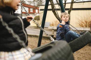 Sister swinging with brother having disability in park - MASF30444