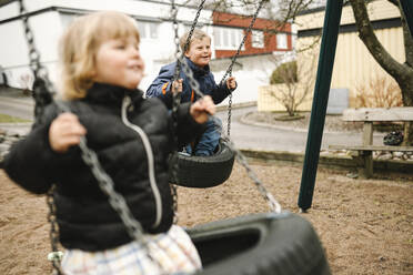 Verspielter Bruder und Schwester haben Spaß auf der Reifenschaukel im Park - MASF30445