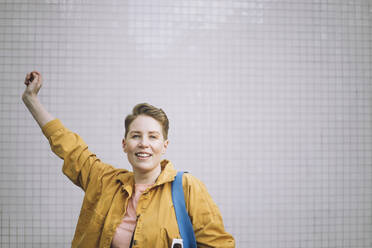 Portrait of cheerful mature woman with hand raised against wall - MASF30486