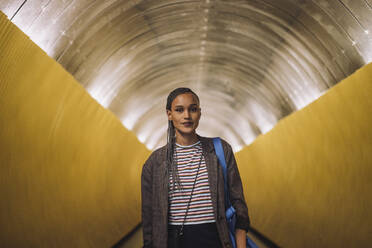 Portrait of smiling young woman with braided hair standing in subway tunnel - MASF30491