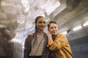 Porträt eines lächelnden lesbischen Paares, das in einem beleuchteten Tunnel steht - MASF30492
