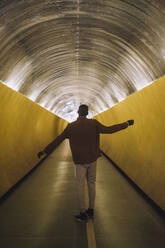 Rückansicht in voller Länge eines jungen Mannes, der in einem U-Bahn-Tunnel tanzt - MASF30513