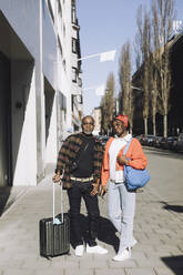 Full length portrait of father and daughter standing on footpath during sunny day - MASF30543