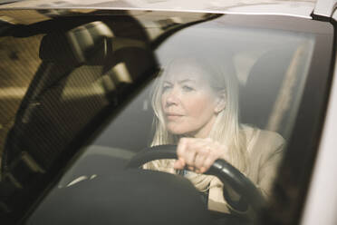 Curious businesswoman driving car seen through windshield - MASF30656