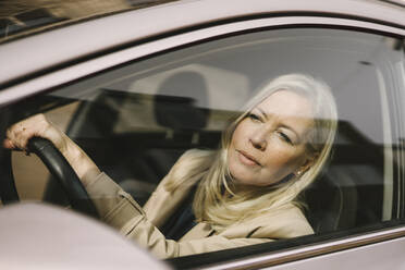 Blonde Geschäftsfrau schaut durch ein Autofenster - MASF30657