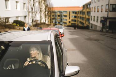 Geschäftsfrau im Auto sitzend durch die Windschutzscheibe gesehen - MASF30658