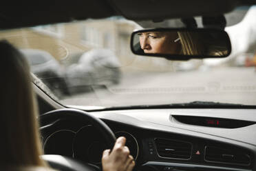 Reflexion einer Geschäftsfrau, die ein Auto fährt, im Rückspiegel gesehen - MASF30663
