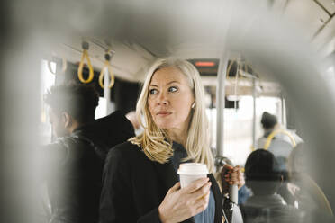 Nachdenkliche Geschäftsfrau mit Einwegbecher in der Hand auf dem Weg zum Bus - MASF30675