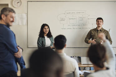 Männliche und weibliche Schüler unterhalten sich mit Freunden während einer Fragestunde im Klassenzimmer - MASF30727