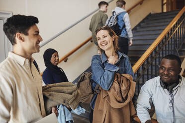 Glückliche multirassische Freunde, die sich im Treppenhaus der Universität unterhalten - MASF30766