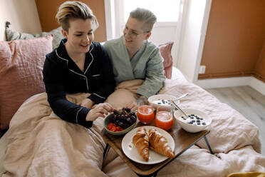 Lesbisches Paar genießt das Frühstück im Bett zu Hause - MASF30804