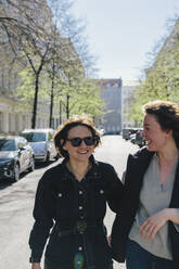 Fröhliches lesbisches Paar auf der Straße in der Stadt an einem sonnigen Tag - MASF30816
