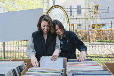 Lächelndes lesbisches Paar wählt Platten am Marktstand aus - MASF30819
