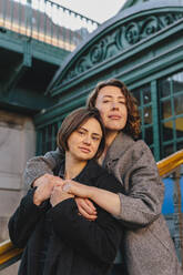 Porträt eines lesbischen Paares, das sich auf einer Treppe in der Stadt umarmt - MASF30830