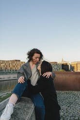 Lesbian couple embracing on rooftop against clear sky - MASF30831