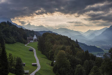 Deutschland, Bayern, Wamberg, Wolken über einer kleinen Straße, die zu einem abgelegenen Dorf im Wettersteingebirge führt - RUEF03682