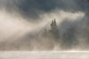 Germany, Bavaria, Thick fog floating over Geroldsee lake at dawn - RUEF03692