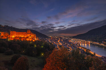 Deutschland, Baden-Württemberg, Heidelberg, Blick auf das Heidelberger Schloss und die umliegende Stadt in der Abenddämmerung - RUEF03703