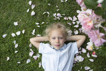 Cute girl with eyes closed lying on grass in rose garden - SVKF00252