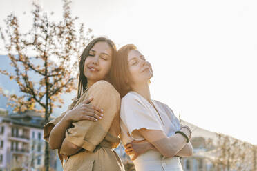 Happy friends standing with eyes closed under clear sky - OMIF00819