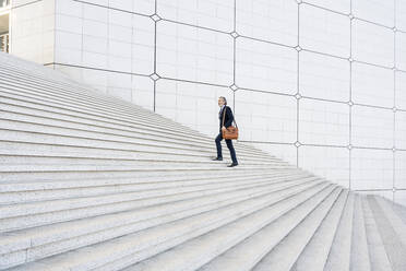 Businessman with bag moving up on steps - OIPF01932