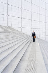 Geschäftsmann mit Tasche auf einer Treppe stehend - OIPF01936