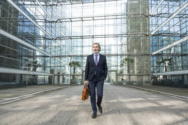 Geschäftsmann mit Tasche vor einem modernen Glasgebäude - OIPF01993
