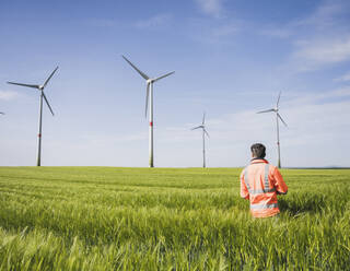 Ingenieur steht an einem sonnigen Tag inmitten von Weizenfeldern - UUF26288