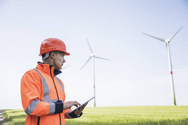 Ingenieur mit Tablet-PC an einer Windkraftanlage vor Ort - UUF26293