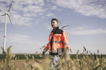 Engineer walking in field on sunny day - UUF26309