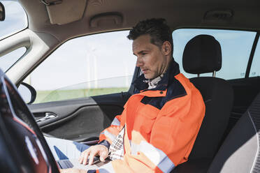 Ingenieur mit Laptop im Auto sitzend - UUF26318