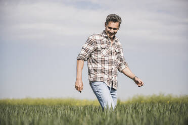 Happy man walking on field - UUF26330