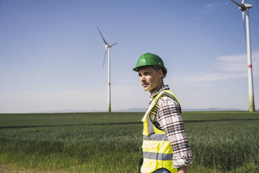 Engineer wearing hardhat standing on field - UUF26338