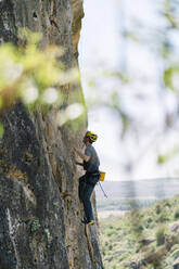 Determined man climbing mountain rock wall - DAMF00979
