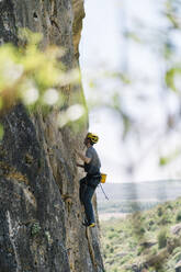 Entschlossener Mann klettert an einer Felswand hoch - DAMF00979