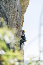 Active man rock climbing on sunny day - DAMF00980