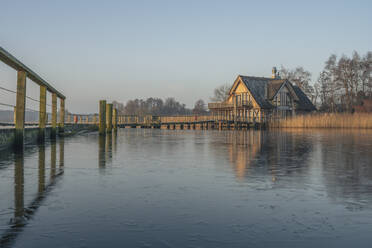 Deutschland, Schleswig-Holstein, Hemmelsdorf, Pier am Hemmelsdorfer See mit Haus im Hintergrund - KEBF02296