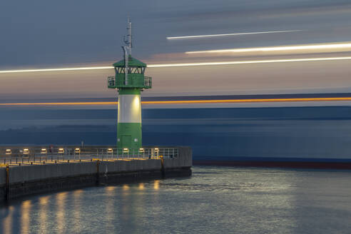 Deutschland, Schleswig-Holstein, Lübeck, Langzeitbelichtung der Fähre beim Passieren des Leuchtturms Travemünde in der Abenddämmerung - KEBF02298