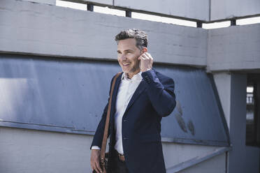 Smiling businessman walking at parking garage - UUF26371