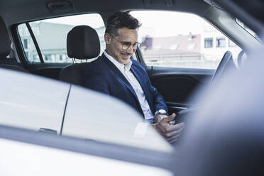 Smiling businessman sitting on driver's seat in car - UUF26383