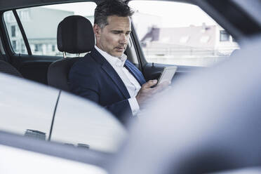 Geschäftsmann, der im Auto sitzend ein Smartphone benutzt - UUF26393