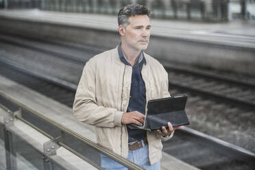 Geschäftsmann mit Tablet-PC auf einem Bahnhof - UUF26424