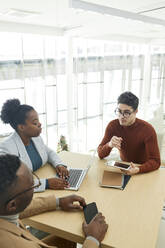 Young businesswoman holding tablet PC discussing plan with colleagues in meeting - DSHF00449