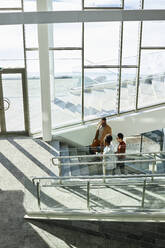 Geschäftsfrau mit Geschäftsleuten, die sich in einem modernen Büro auf einer Treppe bewegen - DSHF00453