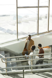 Businessmen with businesswoman moving up on steps in modern office - DSHF00455