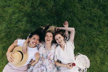 Cheerful women having fun lying in park - OMIF00875